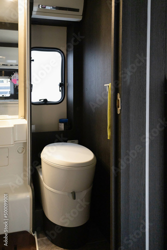 White and black toilet in the interior of a motor home or camper van ready to do a road trip