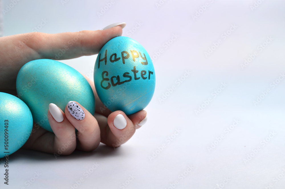 Blue Easter eggs in hands on a gray background.