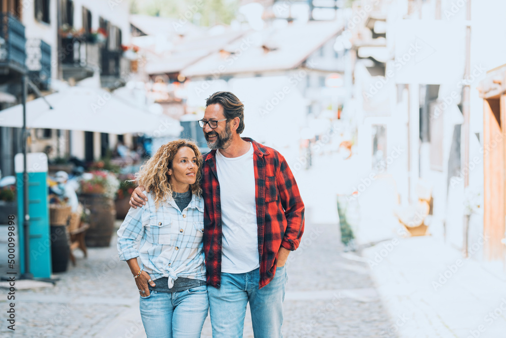 Cute adult couple waling together on the town street. Shopping and tourism activity. Happy people in love and relationship hugging each other and smiling. Cheerful tourists enjoying leisure activity