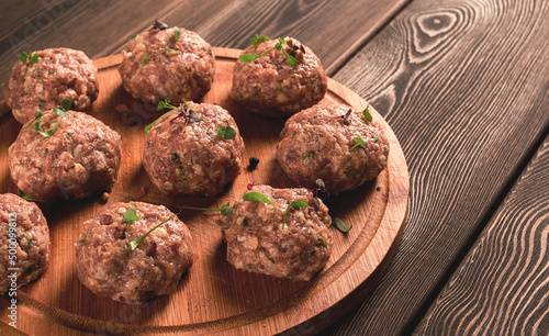 Raw meatballs, with micro greenery, on a cutting board, homemade, rustic, no people,