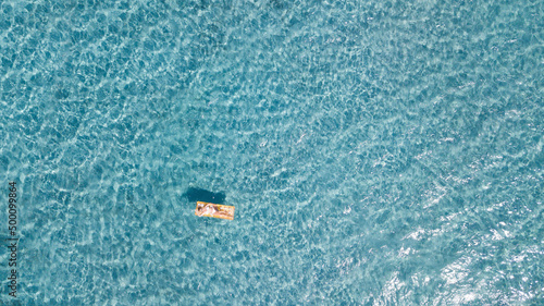 Woman floating on lilo inflatable mattress over blue transparent water surface in summer holiday vacation leisure activity. Female tourist have relax on the ocean. People and beach happy lifestyle