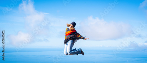 Woman overjoyed jumping crazy for happiness. Concept of freedom and joyful. Female people in leisure activity and fun with blue sky and ocean inbackground. Banner image of travel destination