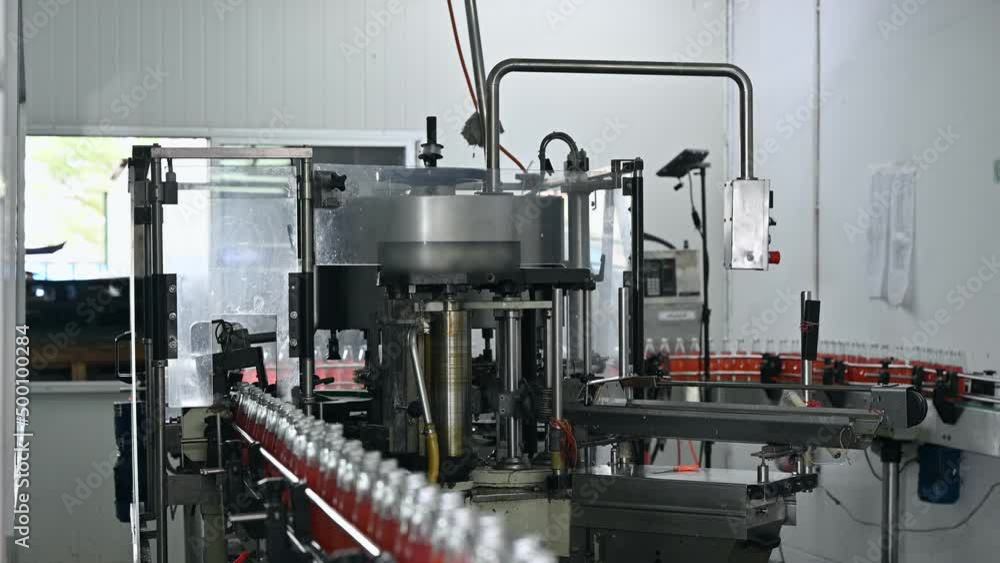 Automatic product labeling machinery working with red juice in production line at bottling factory Automatic product labeling machinery working with red juice in production line at bottling factory