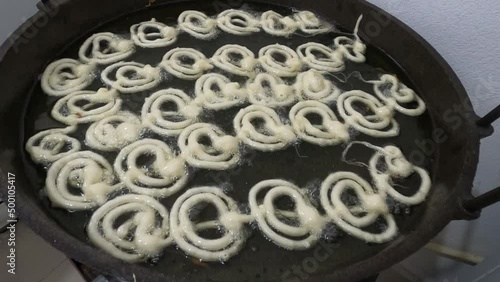 Raw jilapi deep frying 4k video clip.Jilapi making on a hot big pan.Jalebi, also known as jilapi, jilebi, jilipi, zulbia, jerry, mushabak, or zalabia, is a popular Indian sweet snack. photo