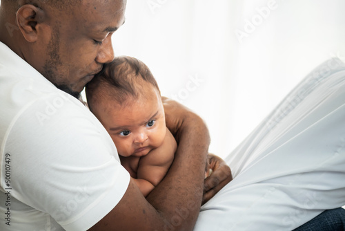An African American father kissing head his 3 months old baby newborn son, with happy and protection, concept to African American family and newborn