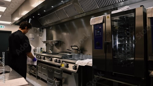 Professional chef in the kitchen of a restaurant. A male chef in a black uniform is working in the kitchen. Slow motion 4K