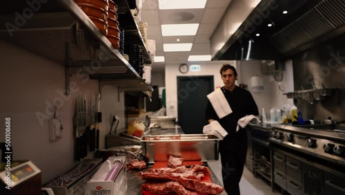 Professional chef in the kitchen of a restaurant. A male chef in a black uniform is working in the kitchen. Slow motion 4K
