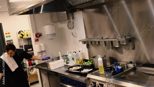 Professional chef in the kitchen of a restaurant. A male chef in a black uniform is working in the kitchen. Slow motion 4K