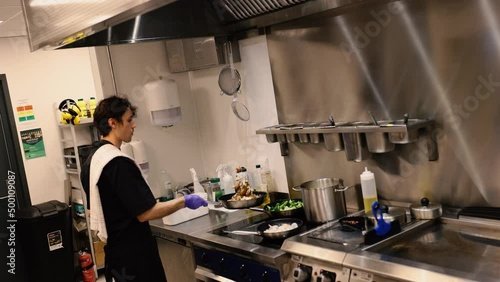 Professional chef in the kitchen of a restaurant. A male chef in a black uniform is working in the kitchen. Slow motion 4K
