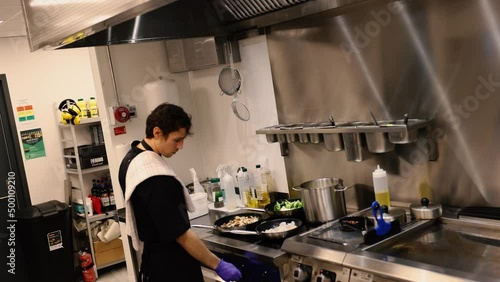 Professional chef in the kitchen of a restaurant. A male chef in a black uniform is working in the kitchen. Slow motion 4K