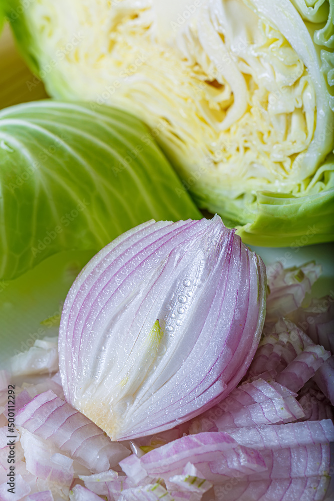Obraz premium Sliced fresh raw white cabbage and onion. Vegetarian healthy tasty food. Chopped vegetables. Top view. Shallow depth of field. Close-up of onion.