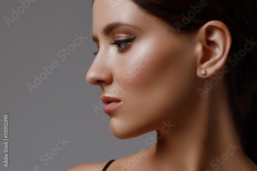 Close-up profile of a caucasian girl with perfect young fresh skin on a gray background. Facial care and face profile correction photo