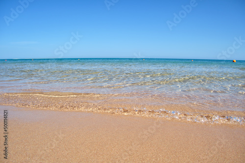 Seascape with surface of blue sea water with small ripple waves crashing on yellow sandy beach. Travel and vacations concept © bilanol