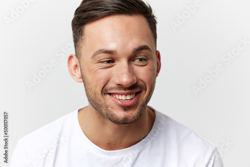Joyful cute happy young tanned handsome man in basic t-shirt laugh at camera posing isolated on over white studio background. Copy space Banner Mockup. People emotions Lifestyle concept. Portrait
