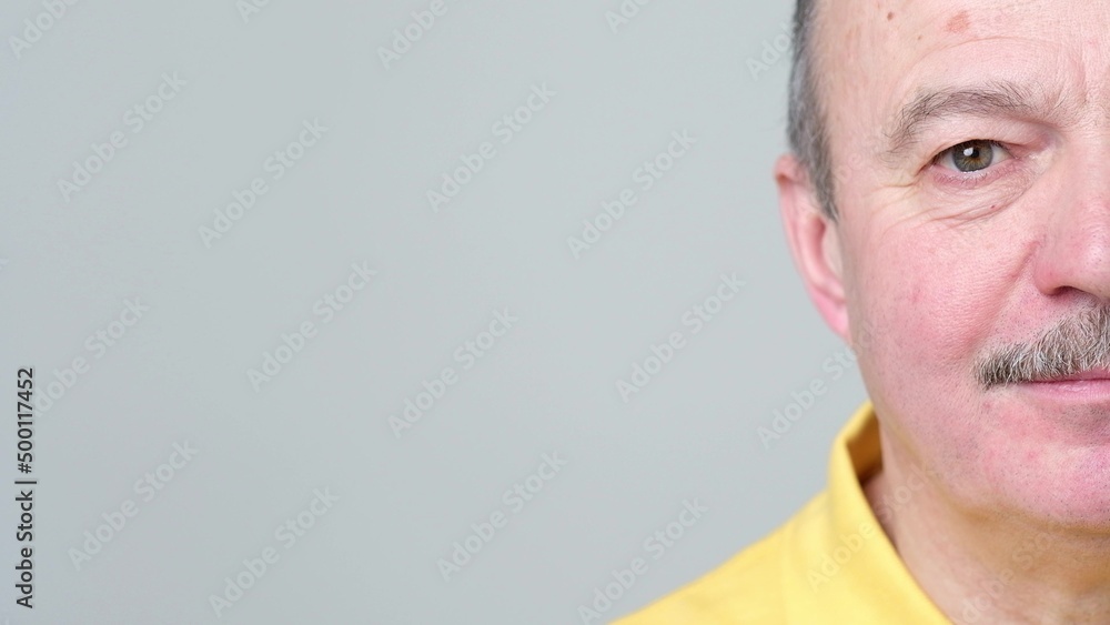 Fototapeta premium Half face of senior man without emotions. He is looking calm and confident