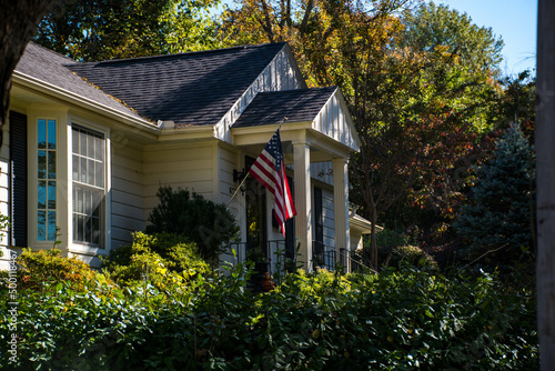 A beautiful white house with the American flag surrounded by yellow and green trees