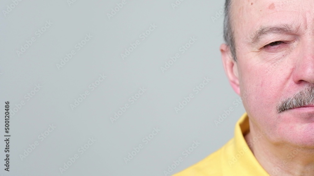 Fototapeta premium Half face of senior man without emotions. He is looking calm and confident