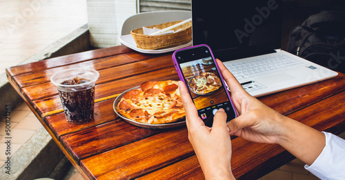 mano de persona influencer con celular tomando foto para historias de plato con comida en restaurante