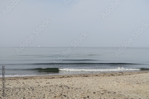 Die See am Priwall in Travemünde ist ruhig. Kleinere Wellen brechen am Strand der Halbinsel an diesem Apriltag. Im Hintergrund ist es dunstig.