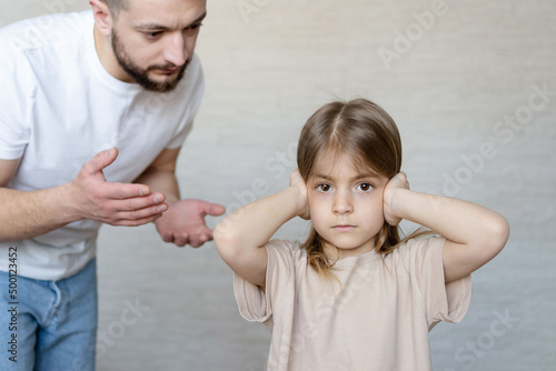 Upset kid girl closing ears not listening parent scolding at home, domestic violence, children and family problems concept