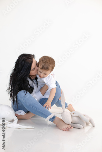 Vertical photo of serious barefoot mother holding and kissing sad son with asperger syndrome. Traumatic experience. photo
