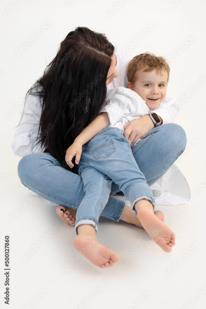 Vertical of black haired woman and little boy, hugging, having fun together. Cuddling, sitting close. White background. Vertical of black haired woman and little boy, hugging, having fun together. Cuddling, sitting close. White background.