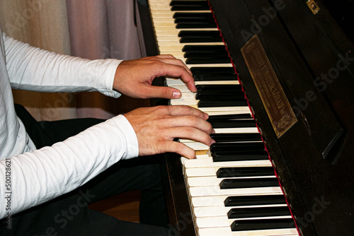 Male hands play the piano, fingers press the keys. Musician pianist accompanist on black and white keyboards on the concert stage.