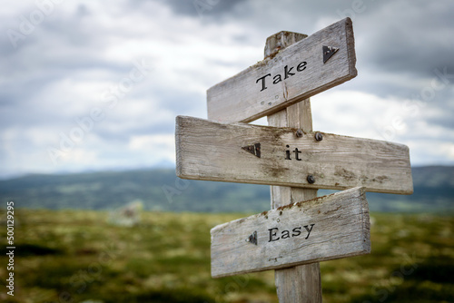 take it easy text quote written in wooden signpost outdoors in nature. Moody theme feeling.