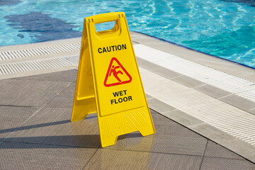 caution wet floor warning sign near swimming pool in hotel