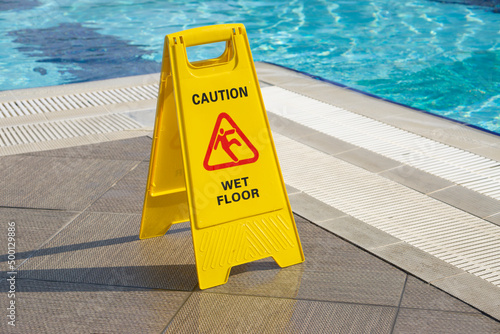 caution wet floor warning sign near swimming pool in hotel photo