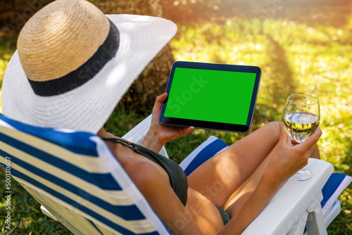 Fotografie, Obraz mockup of woman wearing bikini using digital tablet and drinking wine while rela