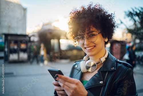 Woman walking in the city streets and using smartphone and headphones
