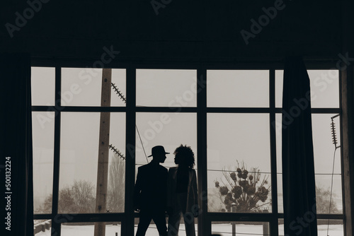 Man and african american woman with curly hair dancing on the background of the window