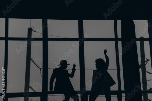 Man and african american woman with curly hair dancing on the background of the window