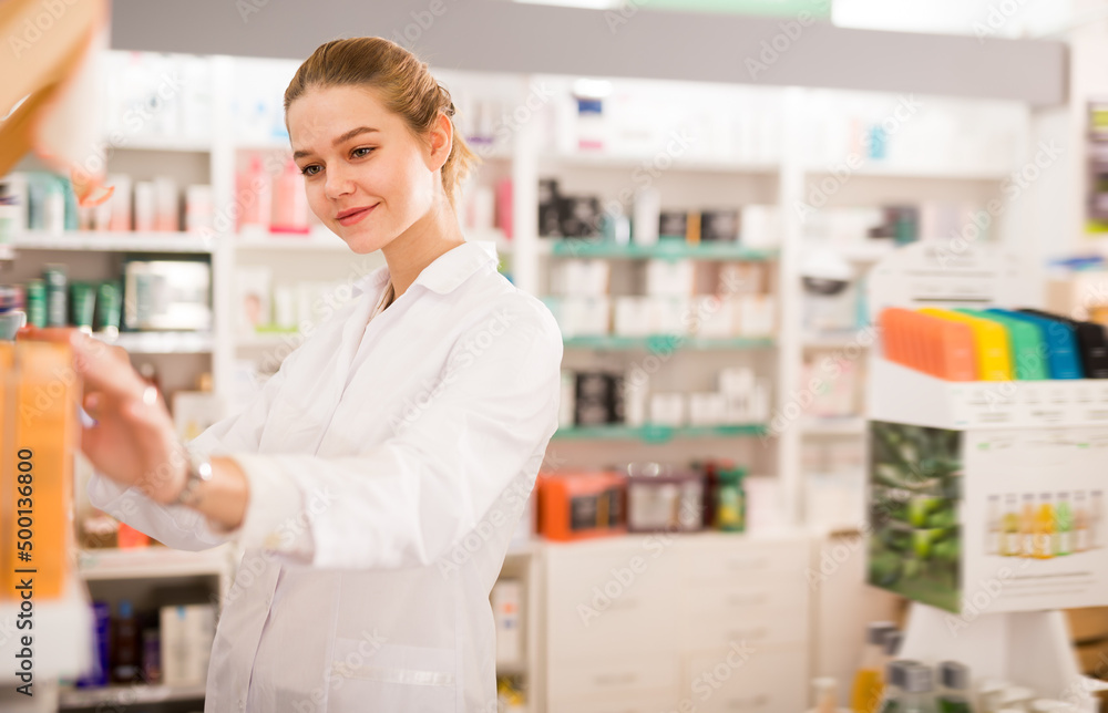 Cheerful pharmacist is browsing rows of body care products in pharmacy