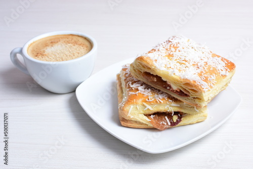 Puff pastry cake with arequipe and cheese, grated coconut, accompanied by Colombian coffee on a wooden background