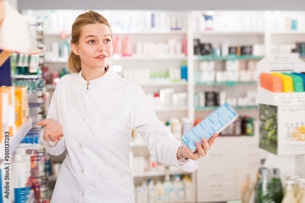 Positive female pharmacist offering help in choosing at counter in pharmacy