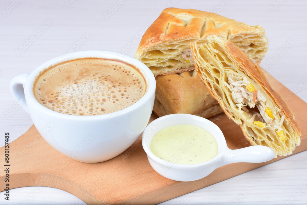 Chicken and cheese puff pastry, accompanied by corn sauce and a cup of Colombian coffee on a wooden background Chicken and cheese puff pastry, accompanied by corn sauce and a cup of Colombian coffee on a wooden background