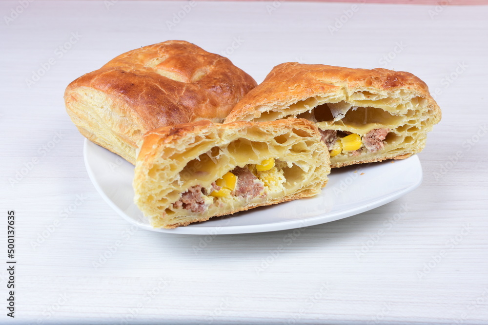 Ham and corn puff pastry, accompanied by sauce on a wooden background Ham and corn puff pastry, accompanied by sauce on a wooden background