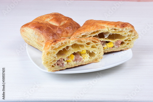 Ham and corn puff pastry, accompanied by sauce on a wooden background