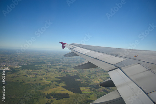 View from inside an airplane to the blue sky and green fields