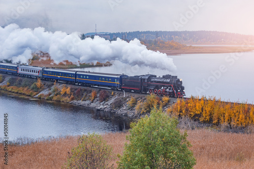 Retro steam train moves along the lake.