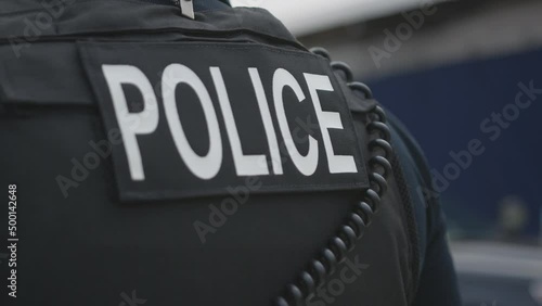 A person wearing a bulletproof vest with a police patch on the back