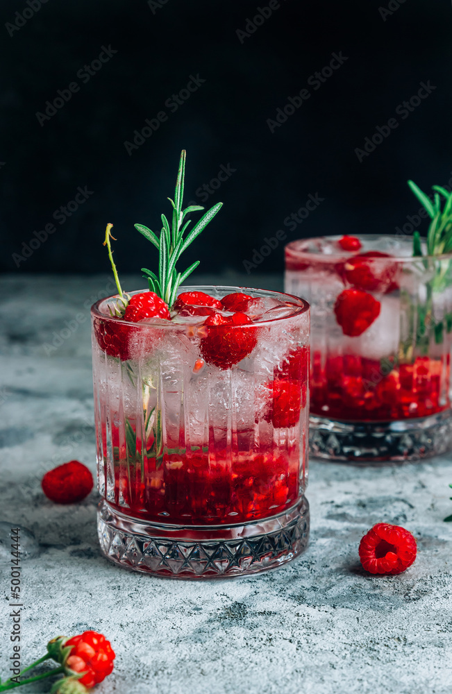 Raspberry lemonade in a glass with ice and fresh rosemary on a concrete background. Raspberry lemonade in a glass with ice and fresh rosemary on a concrete background.