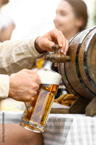 Man pouring beer from barrel into mug, closeup. Octoberfest celebration photo