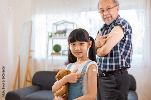 Senior man after vaccination and granddaughter at home. Virus protection. COVID-2019.Vaccination in the shoulder of child patient at home.