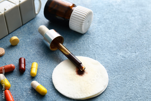 Fotografía Pills, bottle and pipette with iodine on blue background