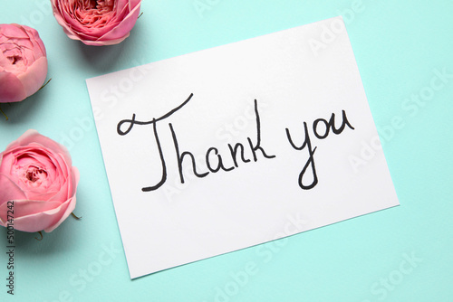 Fotografie Sheet of paper with text THANK YOU and flowers on blue background