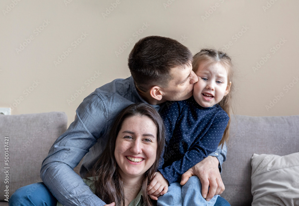 Lifestyle family. Mom dad and daughter are sitting on the couch and hugging.
