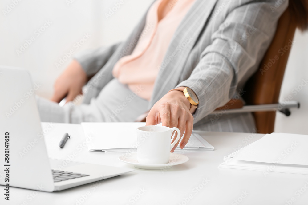 Young secretary taking cup of coffee from table in office, closeup Young secretary taking cup of coffee from table in office, closeup